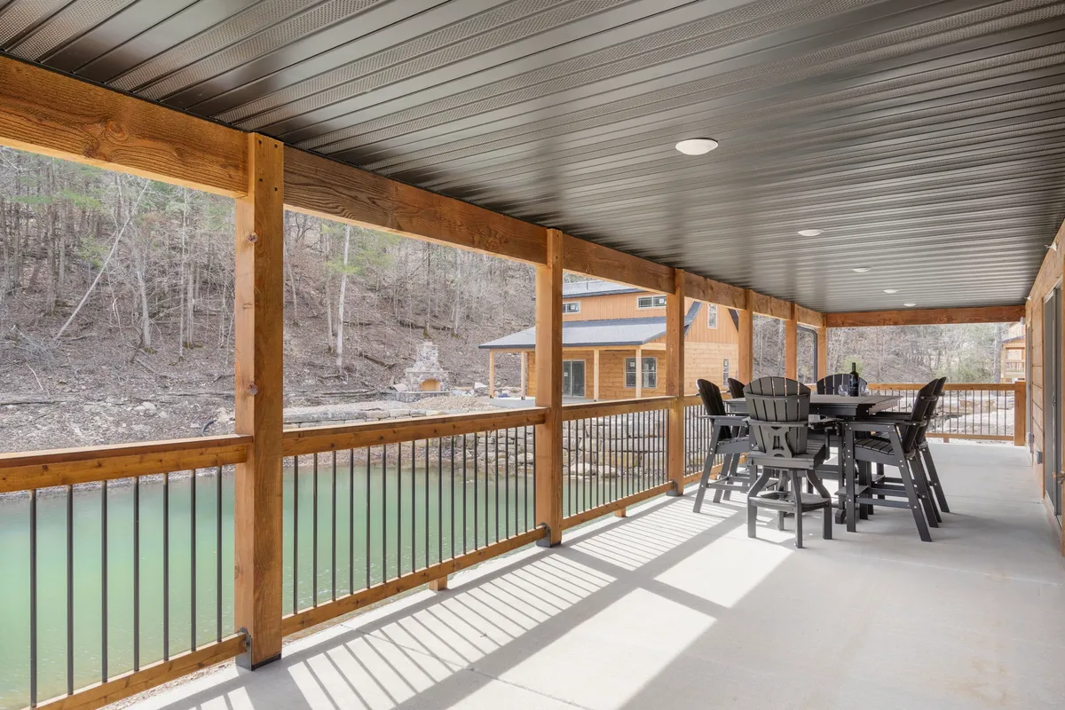 The photo features a tranquil deck with a wooden railing, outdoor dining table, and serene water views surrounded by nature. It embodies the essence of relaxing outdoors, enjoying meals, and soaking in the natural Ozark scenery.