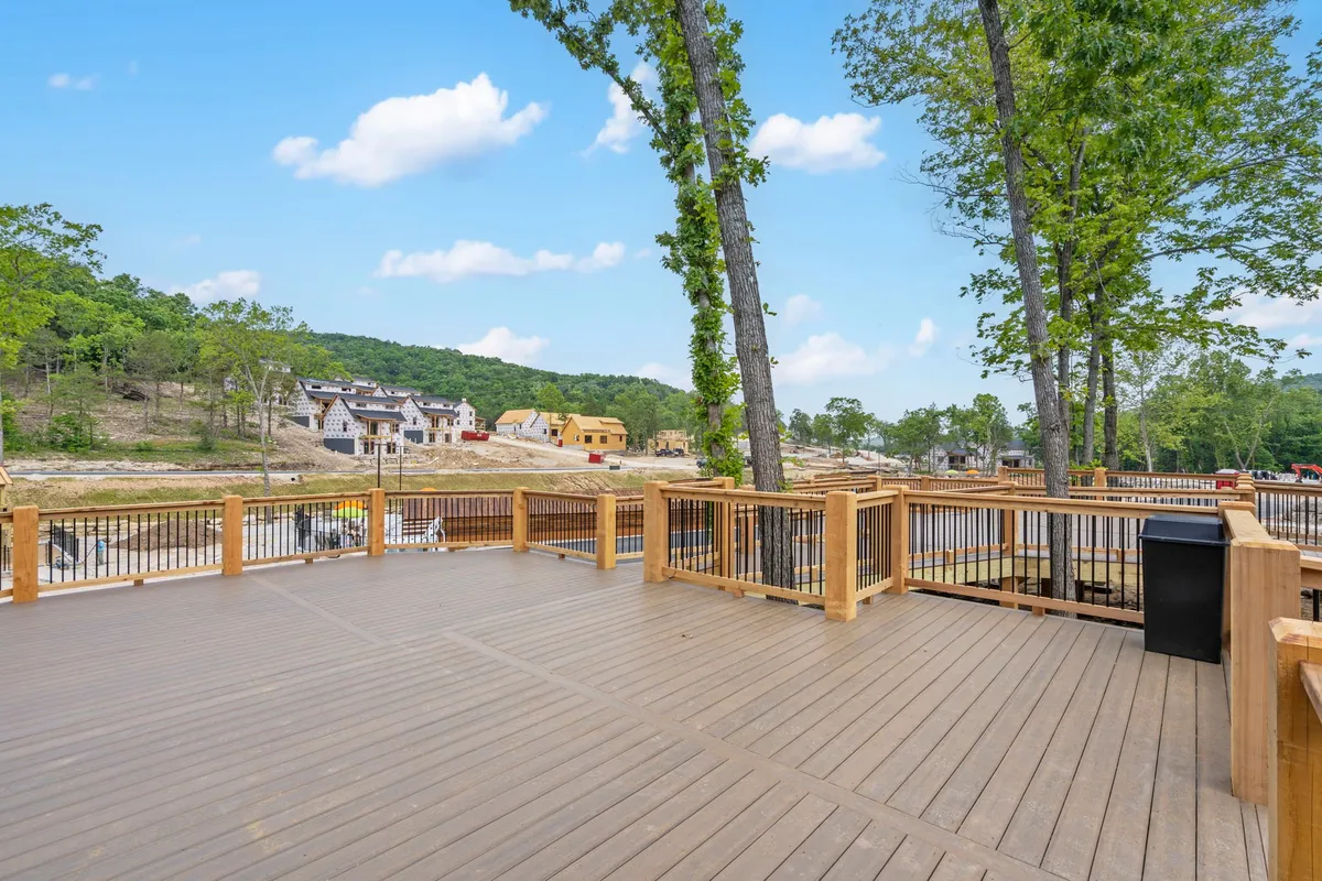 A welcoming wooden deck surrounded by lush trees with views of nearby houses, perfect for outdoor gatherings, barbecues, or simply relaxing in nature. The scene captures the warmth and community spirit of the resort's outdoor amenities.