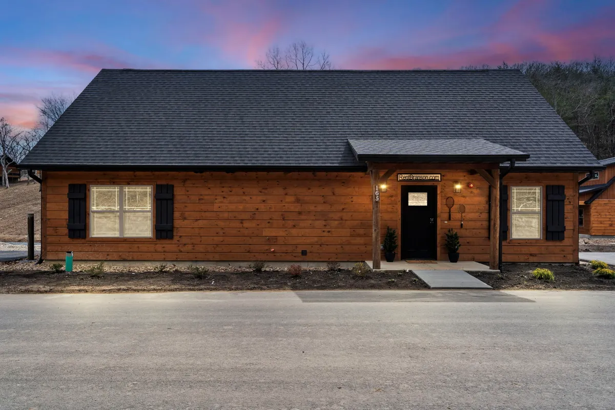 This image shows the wooded exterior of a cabin with a welcoming front porch and landscaped entry, suggesting a space where family gatherings and evening relaxation take place. The setting feels warm and communal, ideal for exploring the property and enjoying outdoor experiences.